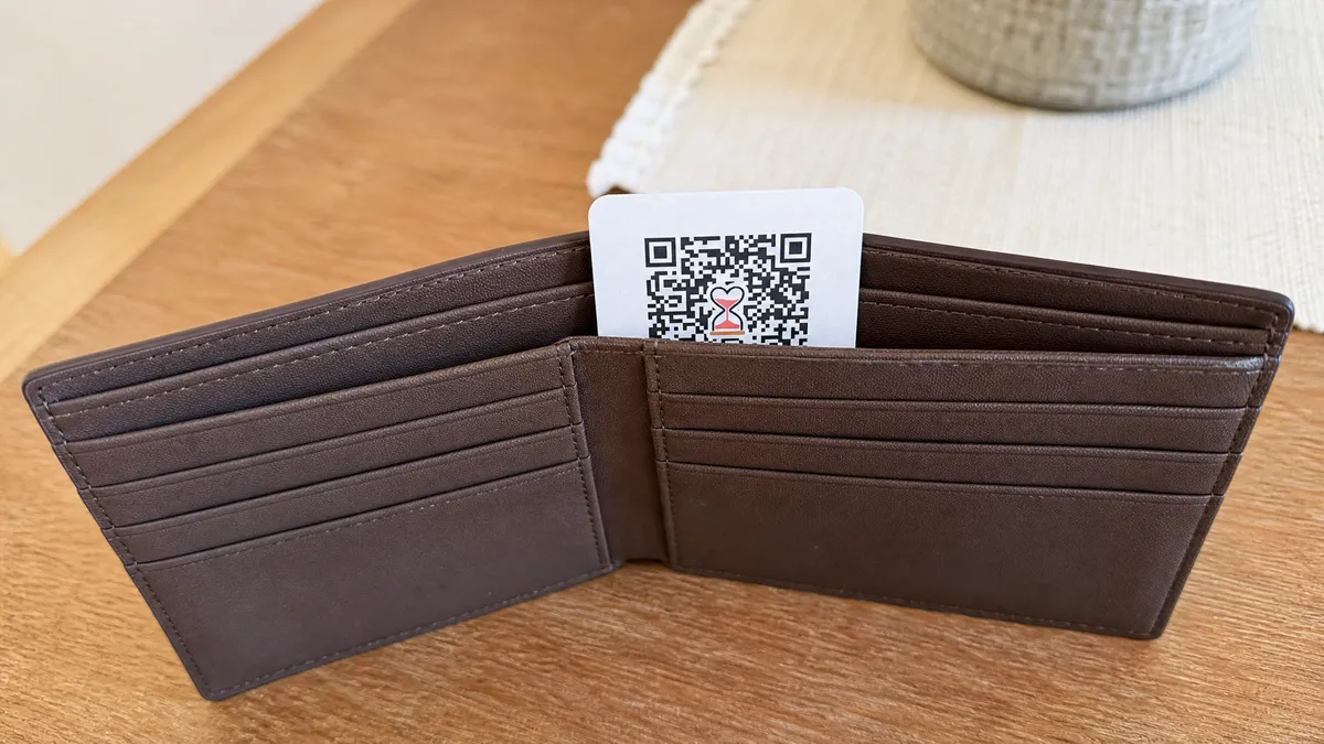Carteira marrom aberta com cartão de QR Code encaixado verticalmente no compartimento de notas